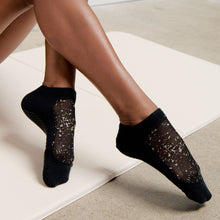 Cargar imagen en el visor de la galería, Shashi black sheer pilates grip socks with gold star design on studio mat