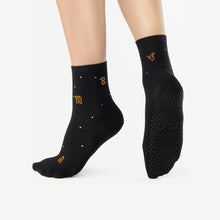 Cargar imagen en el visor de la galería, Black socks with gold logo and textured sole on a white background
